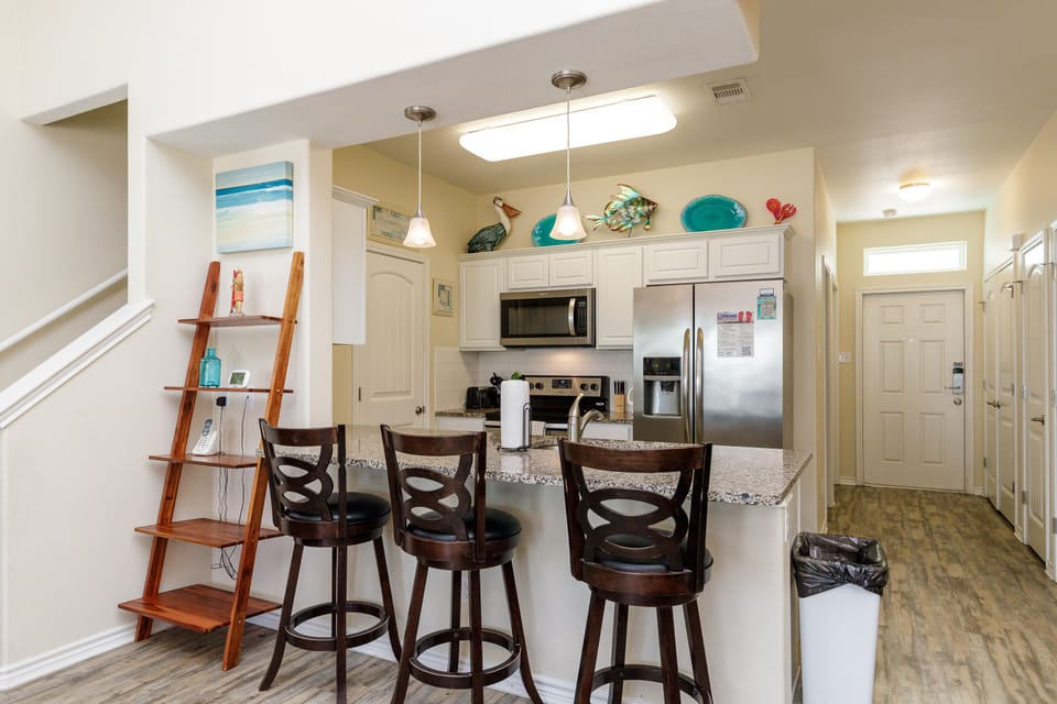 Gather around your bright kitchen island with swivel bar stools, perfect for morning coffee or evening cocktails with coastal-themed touches throughout.