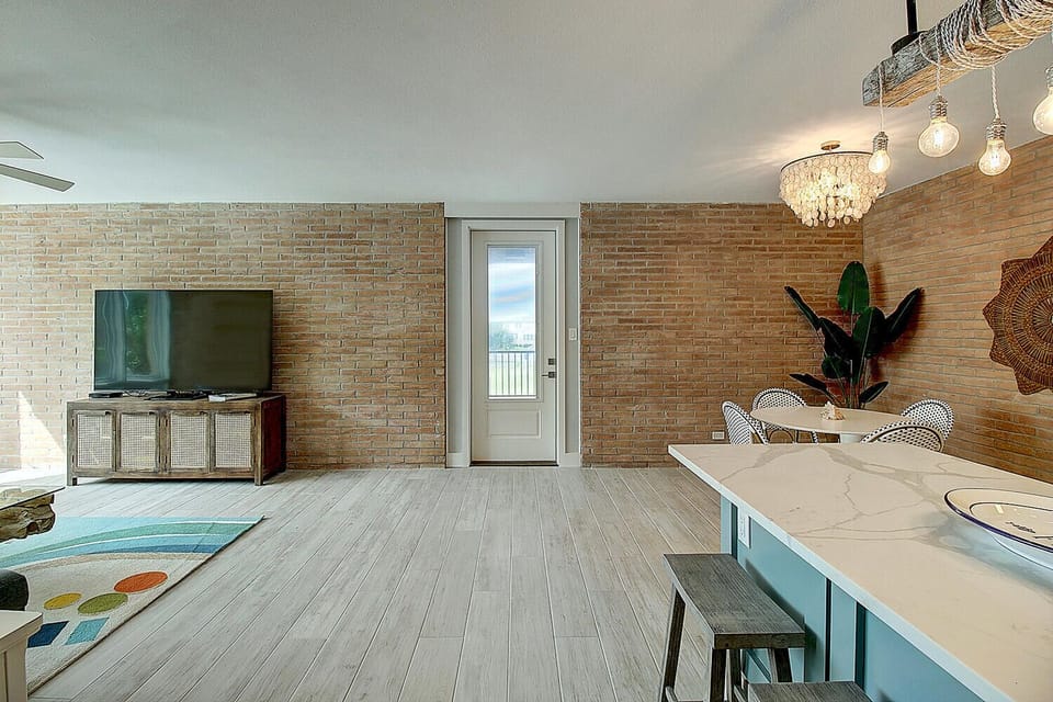 Unwind in your stylish open-concept space with exposed brick walls, modern lighting, and a cozy seating area perfect for relaxing.