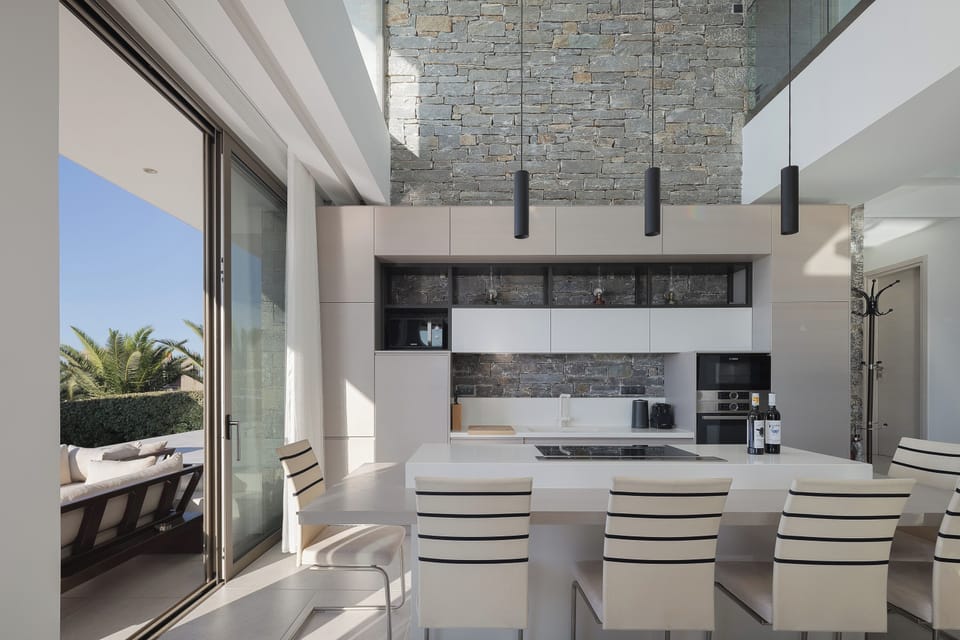 The kitchen features a large central island with six stools, serving as the perfect spot for casual dining or your morning coffee