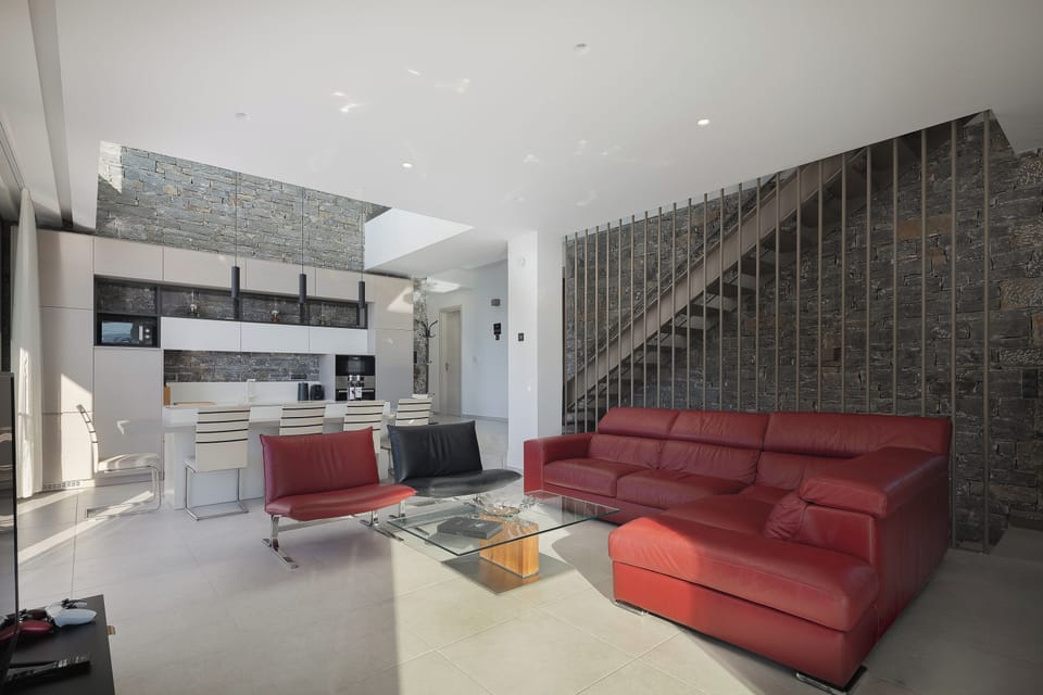 Stepping into the villa, you’ll be welcomed by an open-plan living and kitchen area bathed in natural light from the floor-to-ceiling windows.