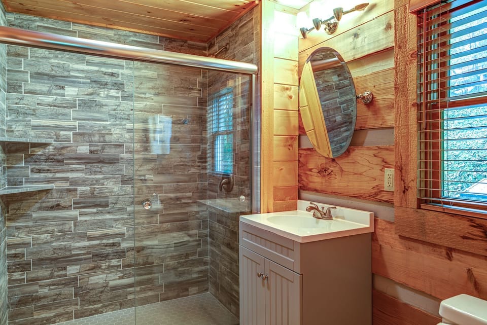 Rustic meets refreshed in this wood-paneled bathroom with a spacious tiled walk-in shower at The Nest At Seven Devils.
