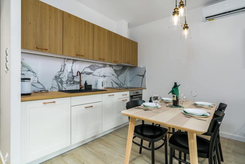 Fully equipped kitchenette with induction cooktop, electric kettle, fridge with freezer, dishwasher, oven and dining area.