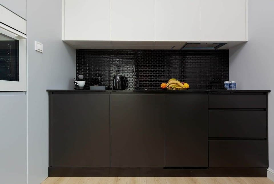 Modern kitchenette with a fridge with freezer, oven, dishwasher, induction hob, extractor hood, coffee machine, electric kettle and washing machine.
