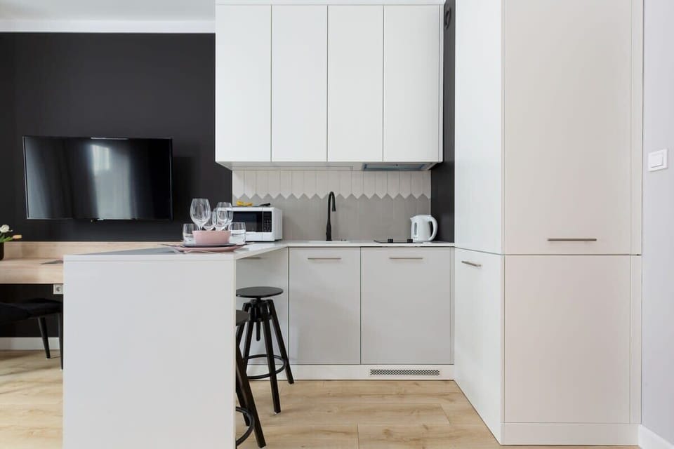 Kitchen worktop with bar stools, fridge freezer, induction hob, extractor hood, microwave and electric kettle.