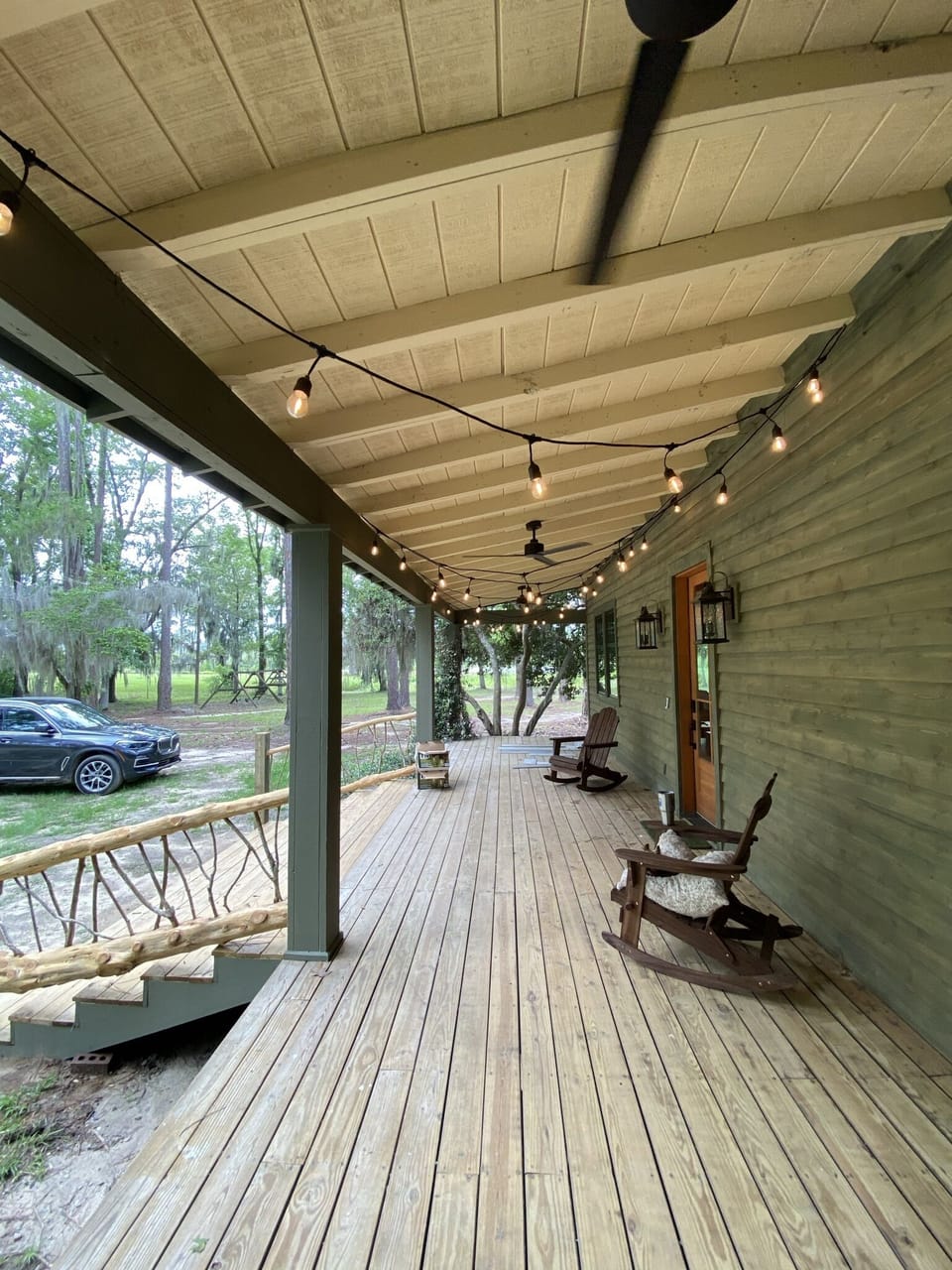 The front porch has rocking chairs and a porch swing with cafe lights and fans