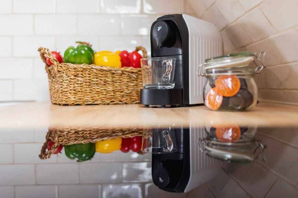 Close-up of the wooden countertop with coffee machine and basket of peppers.