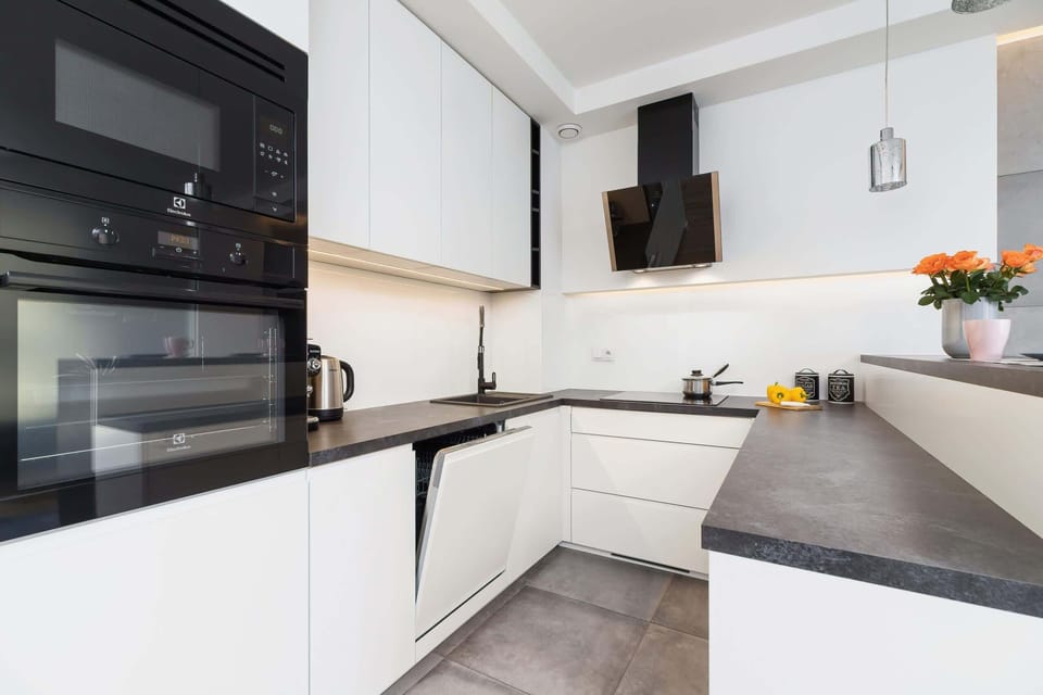 A kitchen featuring white cabinetry, dark countertops, and modern appliances, emphasizing a sleek and functional design.