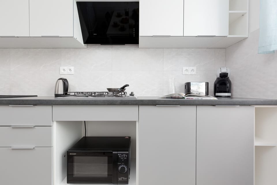 A modern efficient kitchen featuring gray cabinets, a built-in oven, and essential appliances for cooking.