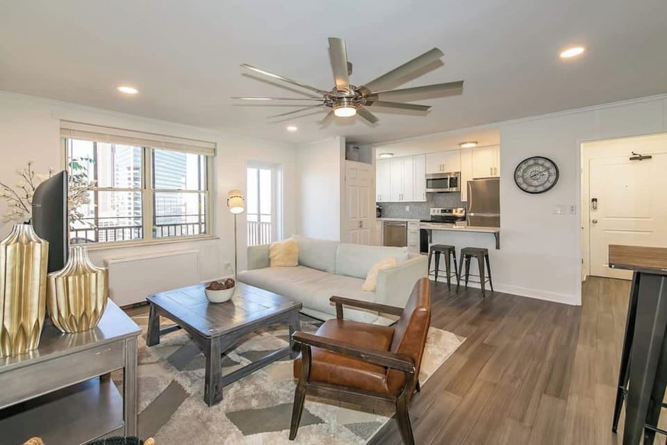 Bright open living area w/ cozy sofa, accent chair & large coffee table under a modern ceiling fan