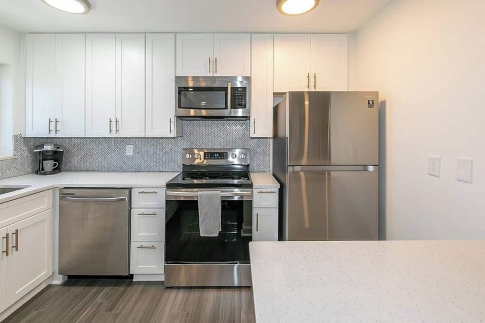 Modern kitchen w/ stainless steel appliances, white cabinetry & sleek finishes