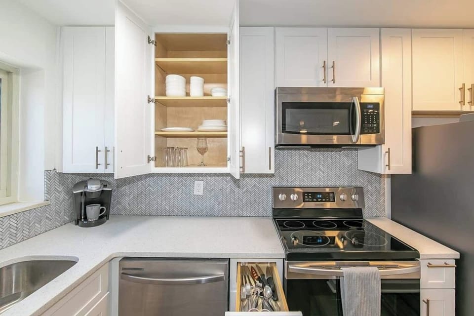 Fully stocked kitchen w/ open cabinetry, dishwasher & cooking essentials