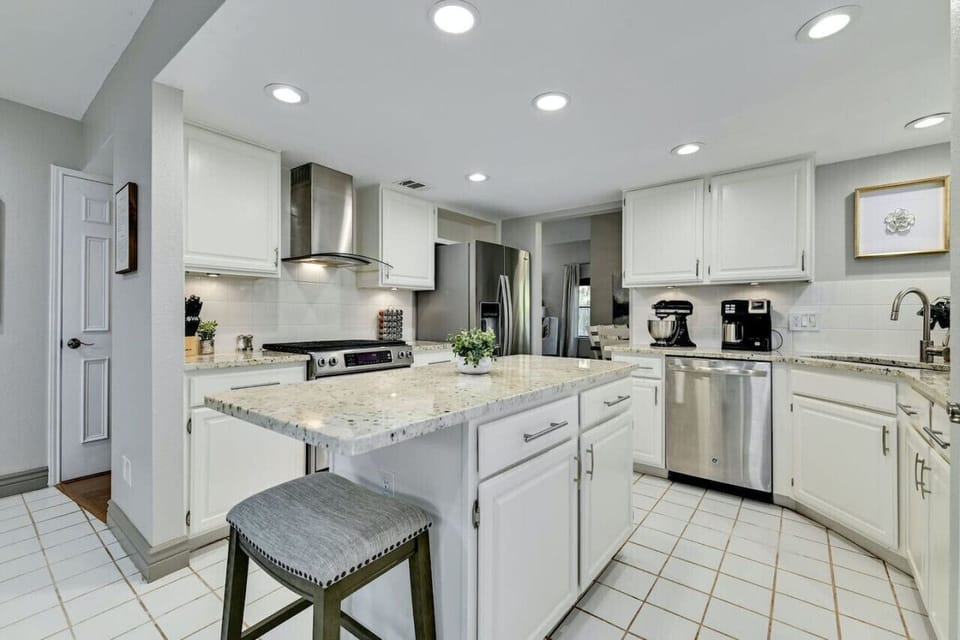 Cook with ease in this bright kitchen featuring a granite island and stainless appliances, elevating your A Stay Above The Rest stay.
