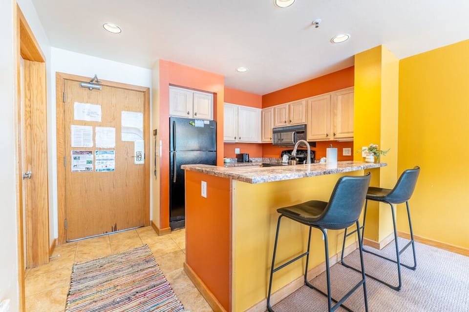 Your vibrant kitchen features a breakfast bar where you can sip morning coffee while surrounded by cheerful orange and yellow walls.