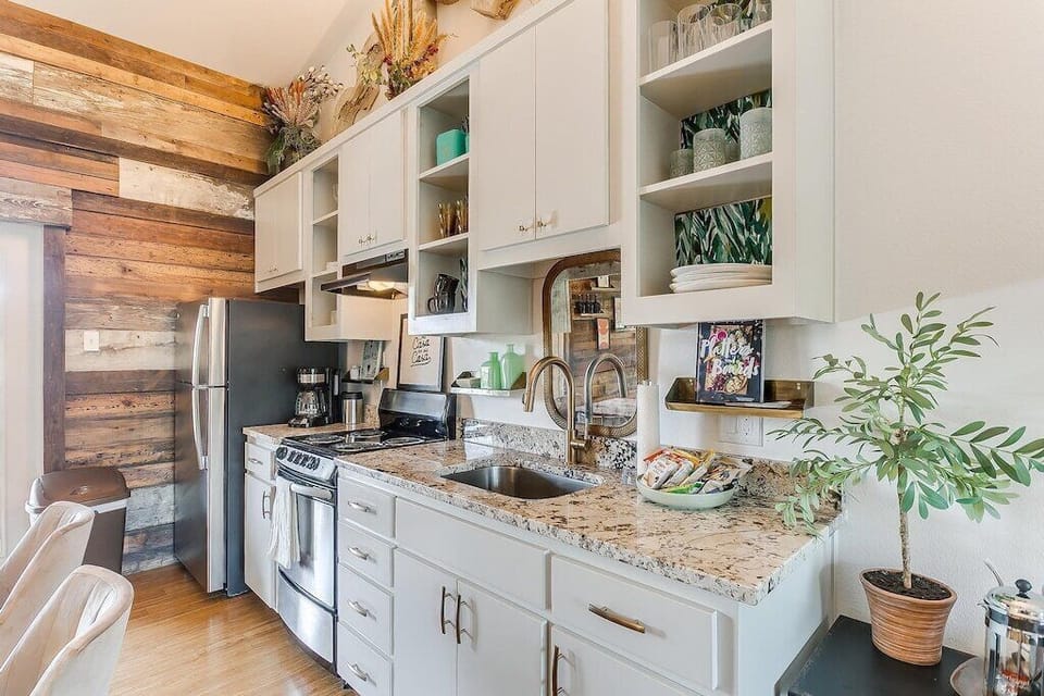 Fully equipped kitchen with granite counters and reclaimed wood accent wall.
