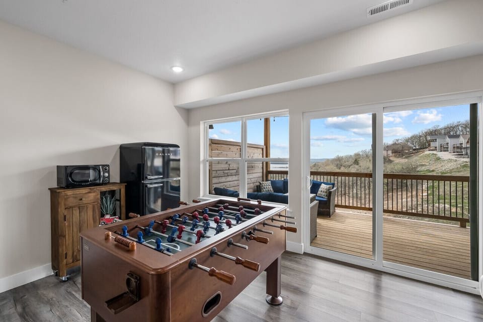 Lower level game area with fridge, microwave, and foosball table