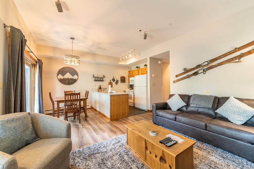 Unwind in your cozy open-plan retreat with plush seating, mountain-themed decor, and a fully equipped kitchen for memorable meals together.