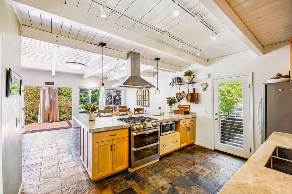 Chef-style kitchen with generous countertop space, gas range, warm wood cabinetry, and garden light—ideal for cooking and entertaining.
