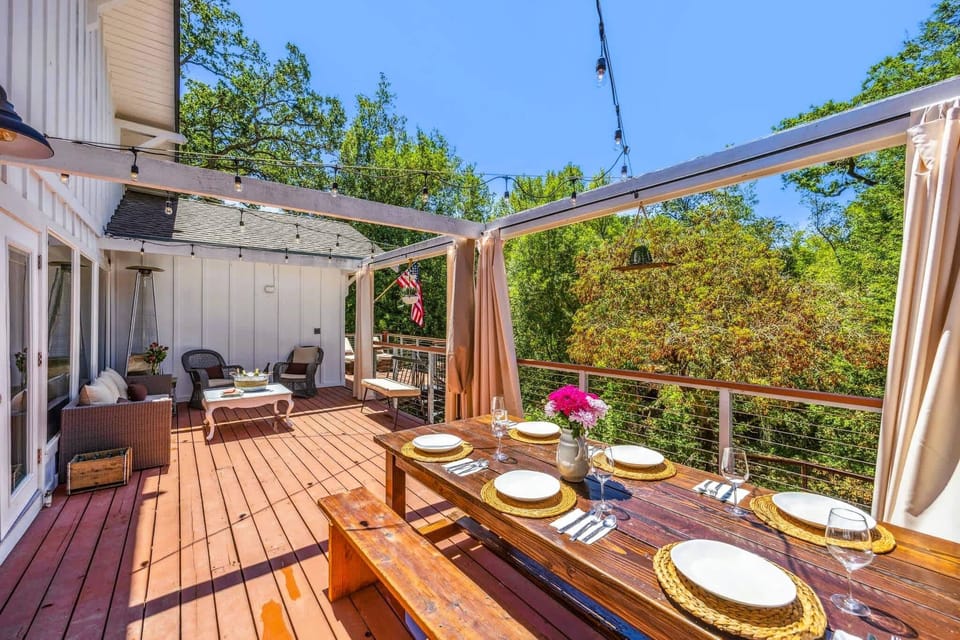 Spacious outdoor deck with dining table, lounge seating, string lights, and leafy views—perfect for entertaining or relaxed evenings.
