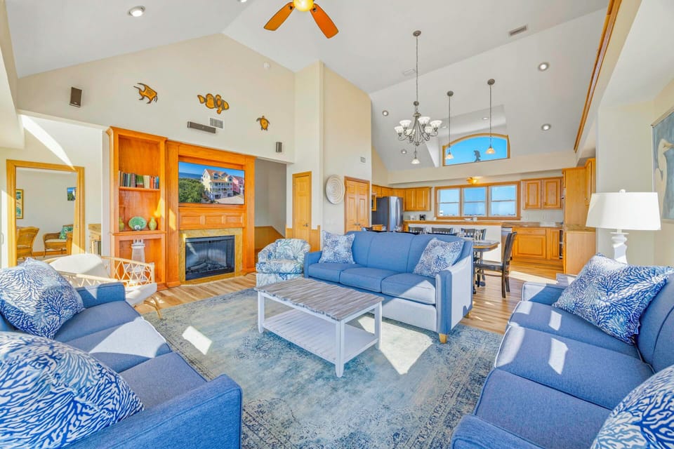 Sink into plush blue sofas in your spacious open-concept living area, where vaulted ceilings and warm wood create perfect mountain retreat vibes.