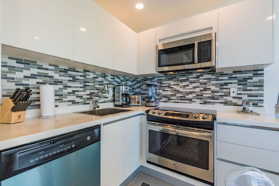 Your fully-equipped kitchen features stainless steel appliances, sleek countertops, and stylish mosaic backsplash, making meal prep a breeze during your stay.