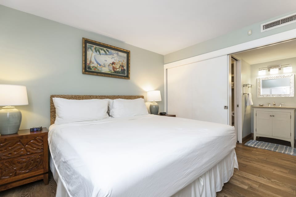 Sink into your plush king bed beneath soothing coastal hues and warm wood accents. Your en-suite bath awaits just steps away, making this retreat feel effortlessly comfortable and inviting.