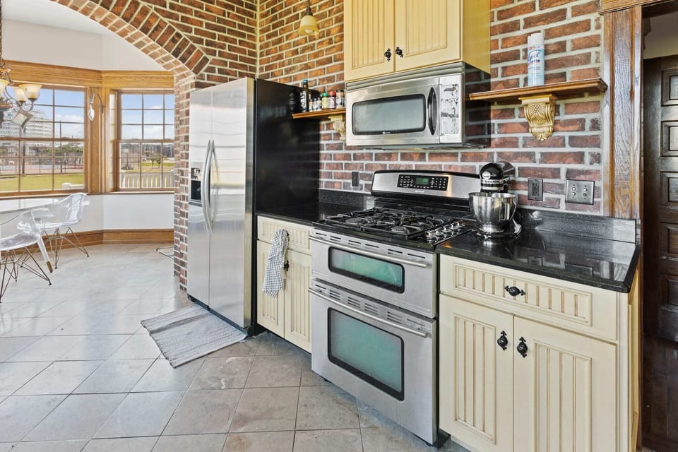Eat-in kitchen with side-by-side refrigerator, dual oven, gas range, new Bosch dishwasher, and unique copper sink