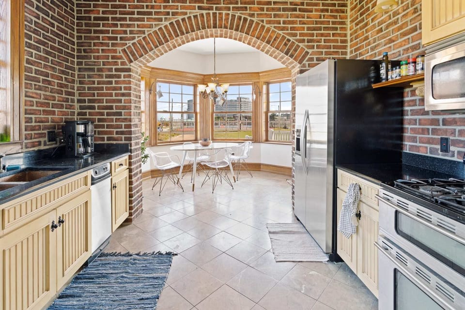 Eat-in kitchen with side-by-side refrigerator, dual oven, gas range, new Bosch dishwasher, and unique copper sink