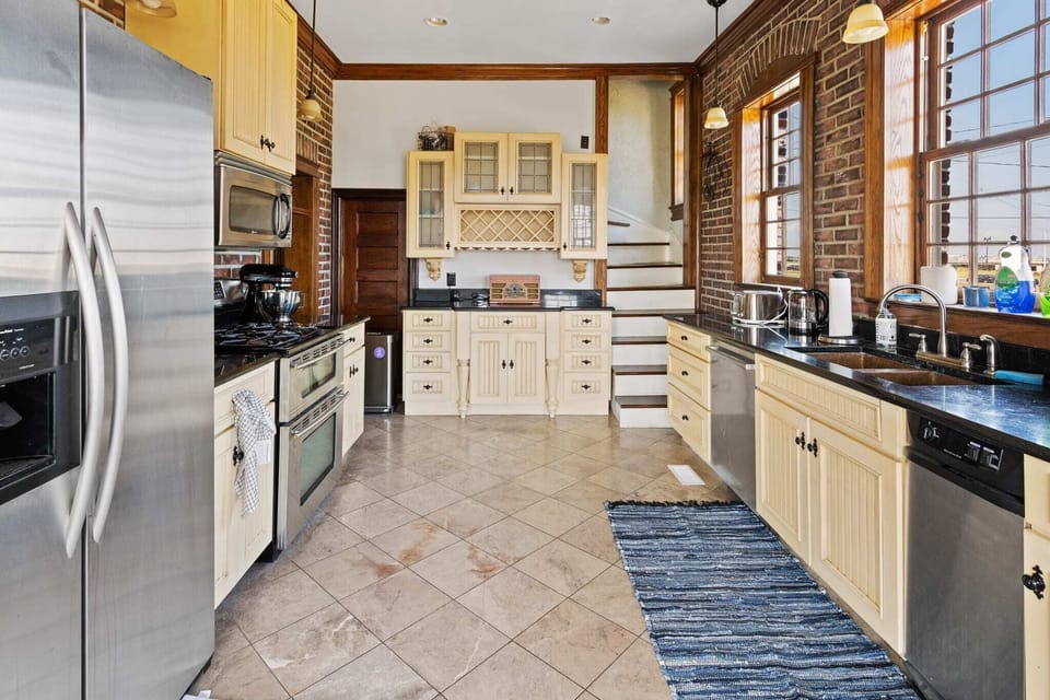 Eat-in kitchen with side-by-side refrigerator, dual oven, gas range, new Bosch dishwasher, and unique copper sink