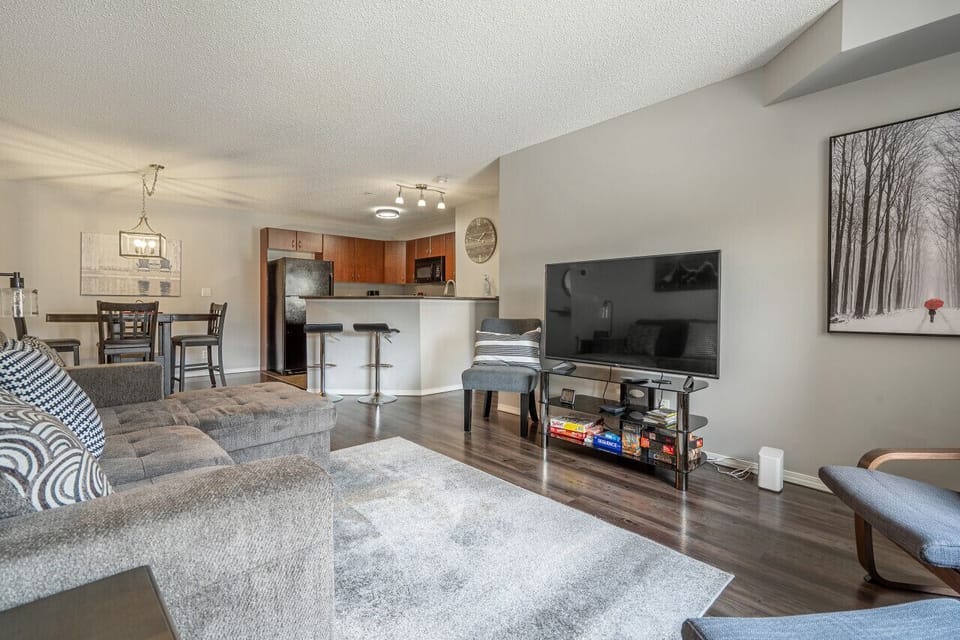 Living room with a smart TV, cozy seating options and a queen-sized pull-out sleeper sofa (all bedding provided.)