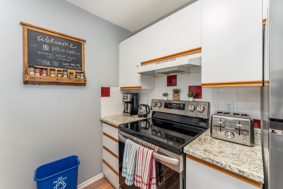 The clean kitchen includes a toaster, coffee maker, fridge, oven, microwave, and dishwasher