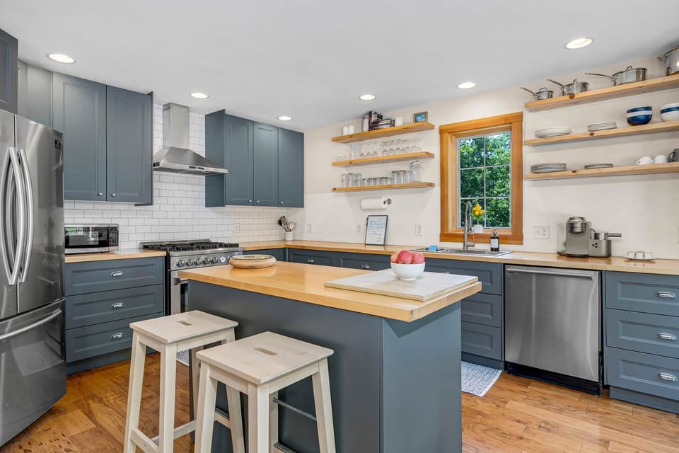 Modern Sunday River kitchen: gas range, custom blue cabinets & bright meal prep space.