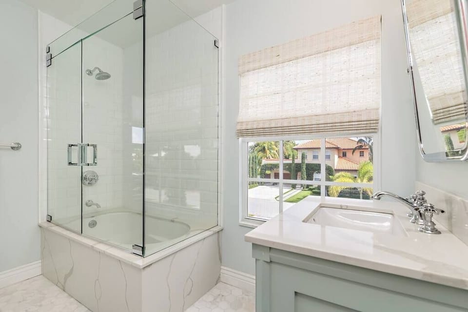 Modern bathroom with a glass-enclosed shower and natural light from the window.