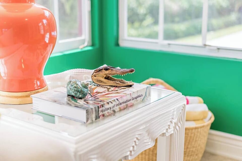 A bright corner featuring a white carved table with decorative items and a green wall backdrop.