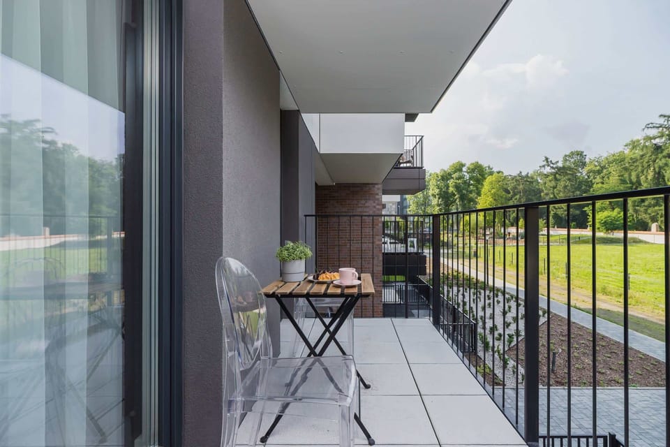 A small balcony with a table and chairs, overlooking a landscaped courtyard.