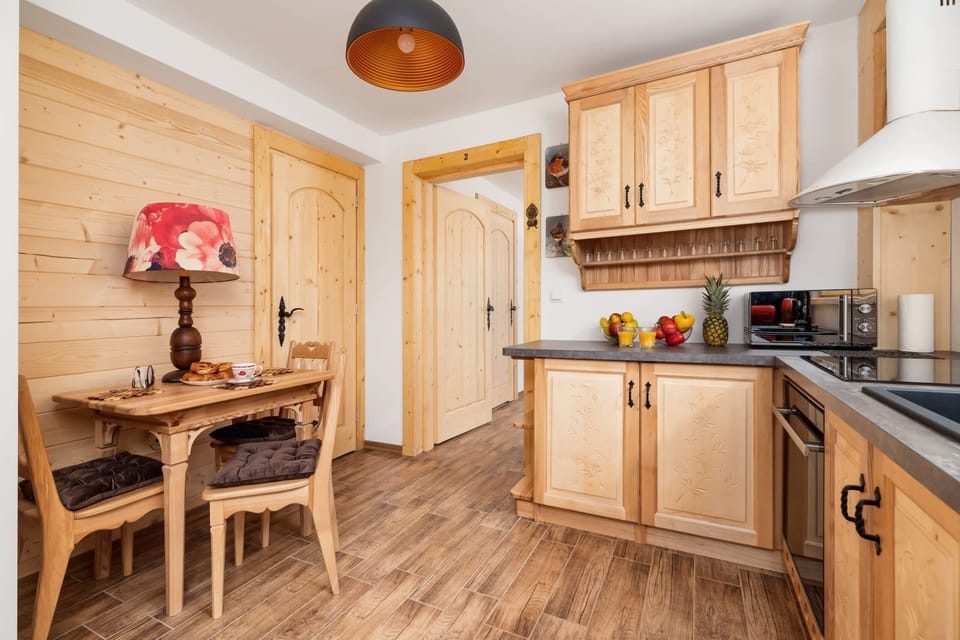 A dining area with a wooden table and chairs, paired with modern appliances in a kitchen that balances tradition and functionality.