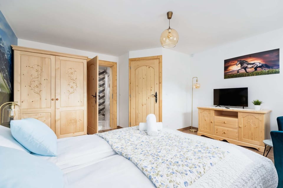 Another angle of a bright bedroom, showing intricate wooden carvings on the furniture and large windows that let in natural light.