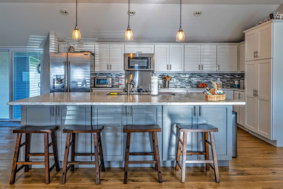 Chef's kitchen with cooking supplies, large island, and ample cabinet space.