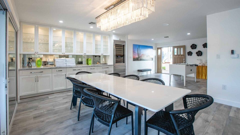 Chic dining: crystal chandelier, glass cabinets, & modern woven chairs.