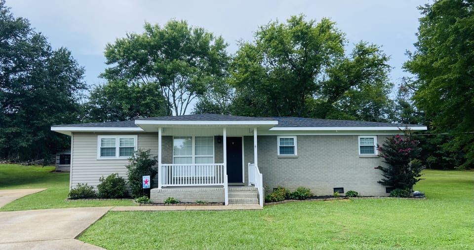 Front of the house with porch and concrete driveway. 