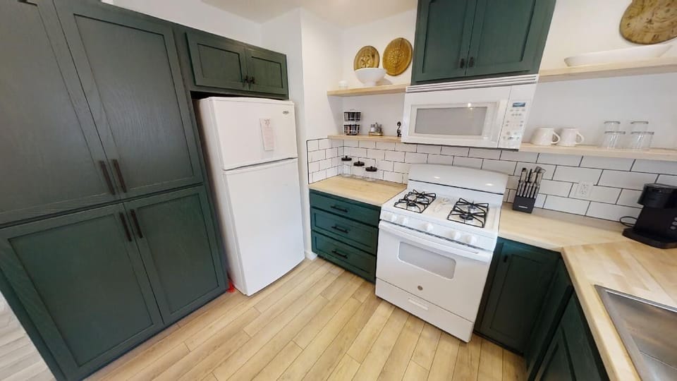 Your fully equipped kitchen awaits with warm wood floors, stylish green cabinetry, and everything you need to cook your favorite meals. Modern appliances and ample counter space make this the heart of your home away from home.