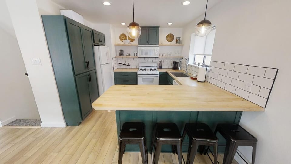 You'll love gathering in this modern kitchen with its butcher-block island, stylish pendant lighting, white subway tile backsplash, and fully equipped appliances—perfect for preparing your favorite meals together.