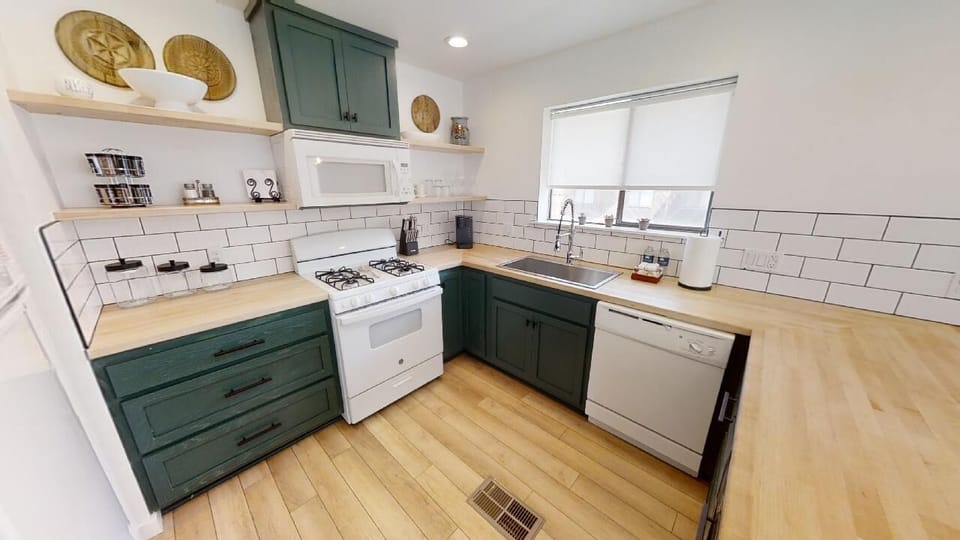Step into your fully equipped kitchen, where charming teal cabinetry meets warm wood countertops and classic subway tile. Cook with ease using the gas stove and modern appliances in this bright, welcoming space.