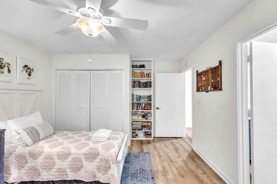 Bright bedroom with a ceiling fan and built-in bookshelf for a cozy stay