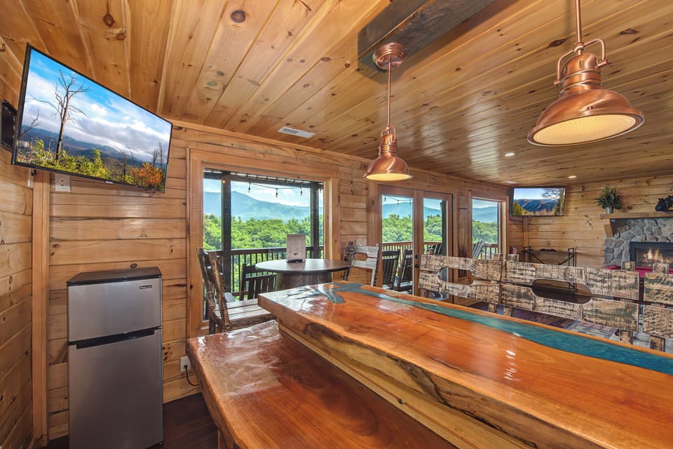 Step into your mountain retreat where a handcrafted live-edge bar invites you to unwind beneath soaring wood ceilings and copper pendant lights. Picture yourself savoring the stunning valley views framed by floor-to-ceiling windows.