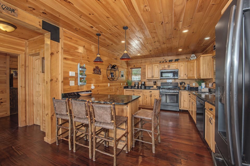 Gather around the rustic island in this warm, fully-equipped kitchen where pine walls and modern appliances blend charm with convenience for your mountain getaway.