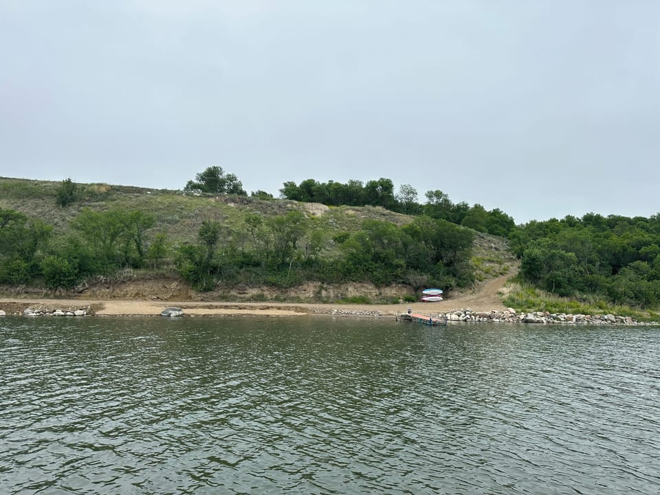 Lakefront from lake. Swim area to left. Kayaks and path to cabin on right.