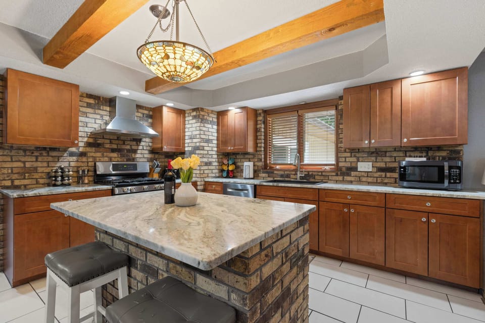 Fully equipped kitchen with warm wood cabinetry, brick accents, and a spacious island perfect for gathering and cooking.