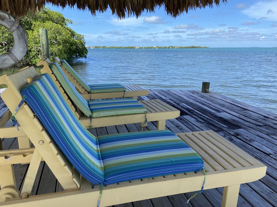 Shady Palapa at the end of the pier into the sea with lounge chairs.