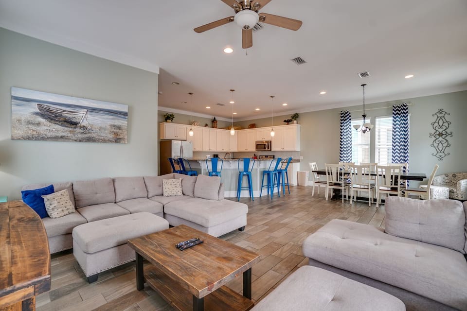 Relax in your spacious open-concept living area where coastal charm meets modern comfort, featuring plush seating and a fully-equipped kitchen perfect for your getaway.