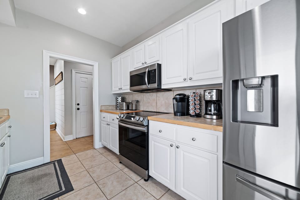 Prepare delicious meals for your loved ones using the newly upgraded stainless steel appliances in the kitchen, perfect for culinary creations.